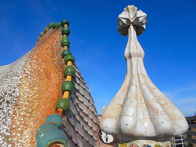 The scaled ridge of the dragon's back on the roof of Casa Batlló, with the bulb-shaped tower topped by a four-armed cross