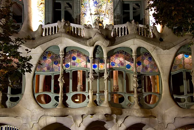The facade of Casa Batlló lit at night, with the balconies and the stained-glass windows of the first floor glowing