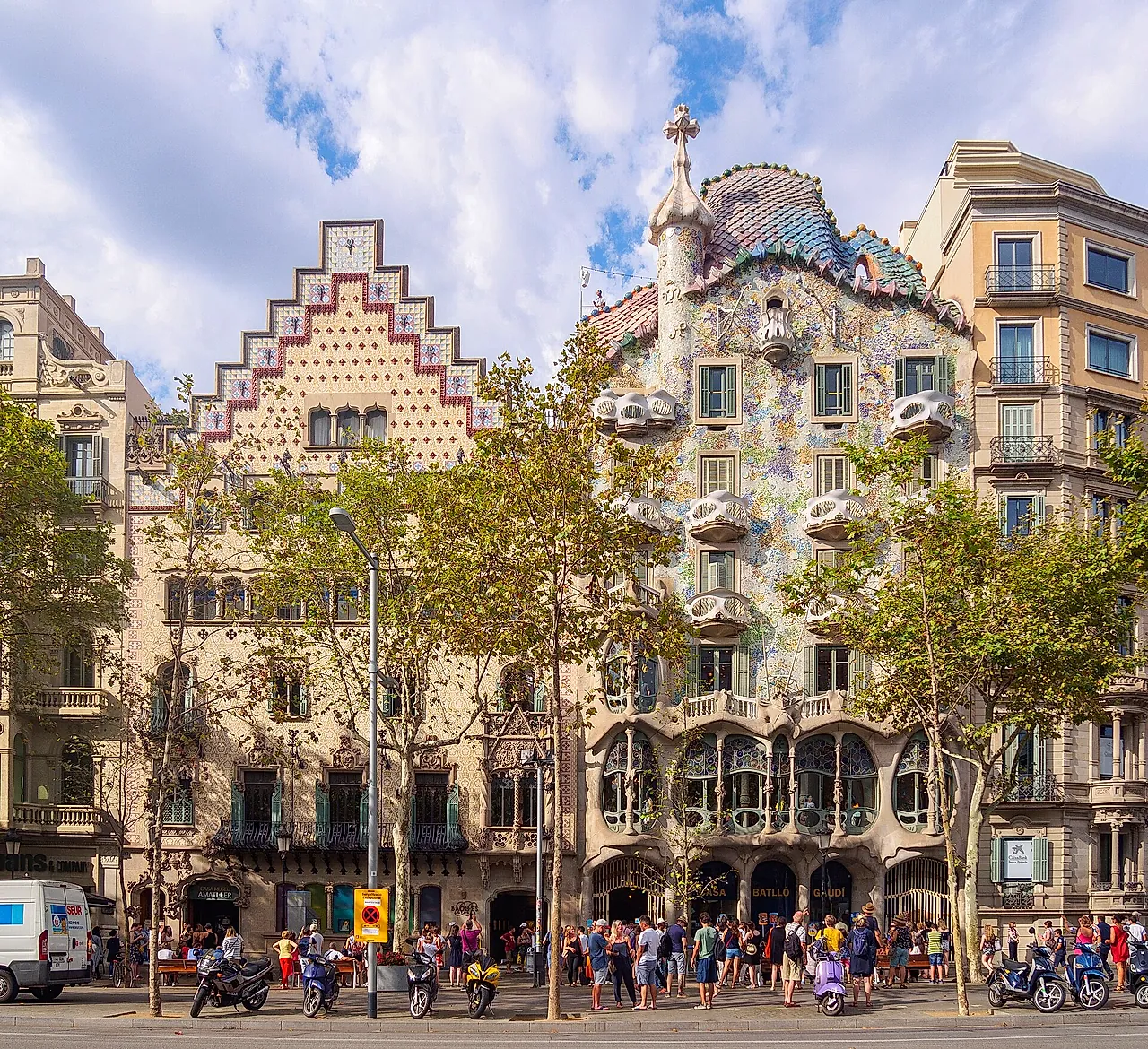 Passeig de Gràcia with Casa Amatller and Casa Batlló side by side under a blue sky, plane trees in front