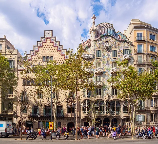 Passeig de Gràcia with Casa Amatller and Casa Batlló side by side under a blue sky, plane trees in front